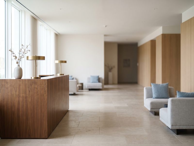 A calm boutique hotel reception with a walnut counter and soft lounge seating.