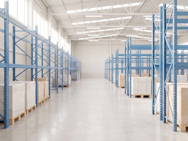 A clean modern logistics warehouse aisle with blue steel racking and a polished concrete floor.
